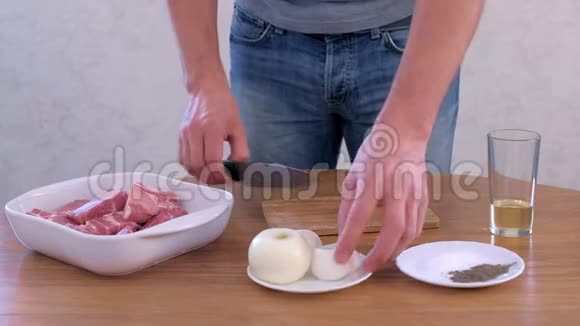 男人在戒指上切洋葱把猪肉切成碎片切碎腌制视频的预览图