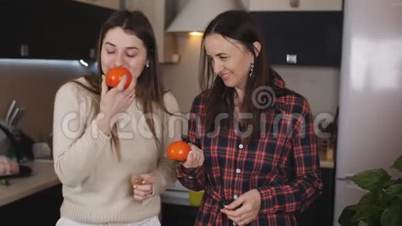两个女孩在厨房里说话在准备沙拉之前闻到西红柿的味道视频的预览图