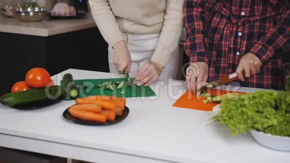 两个女人在厨房里切蔬菜做沙拉健康微笑的女人在家厨房准备午餐视频的预览图