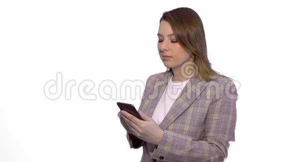 失望的悲伤金发女孩在手机上发短信而站在孤立的白色背景视频的预览图
