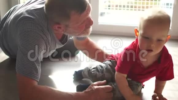爷爷和小孙子坐在地板上玩在家里玩得很开心爷爷和孙子快乐视频的预览图