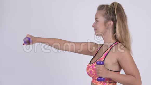 幸福的金发女郎用哑铃锻炼的侧影视频的预览图