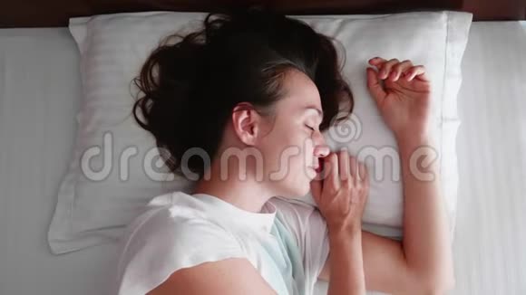 年轻的女人早上醒来在床上伸展身体微笑着视频的预览图