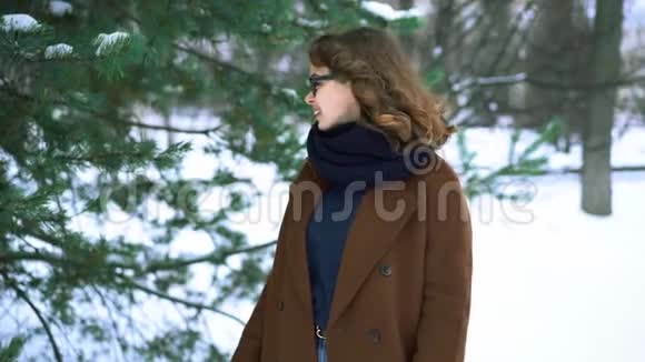 年轻漂亮的时髦女人穿着针织围巾站在公园里微笑冬季时尚视频的预览图