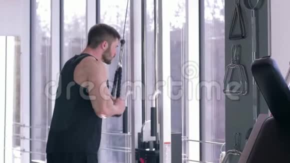 健美运动员锻炼强壮的男性在牵引模拟器上做肌肉锻炼同时在健身房附近锻炼身体视频的预览图