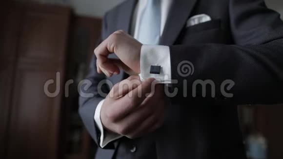 英俊的新郎把他的袖口用袖扣固定在夹克上商人视频的预览图