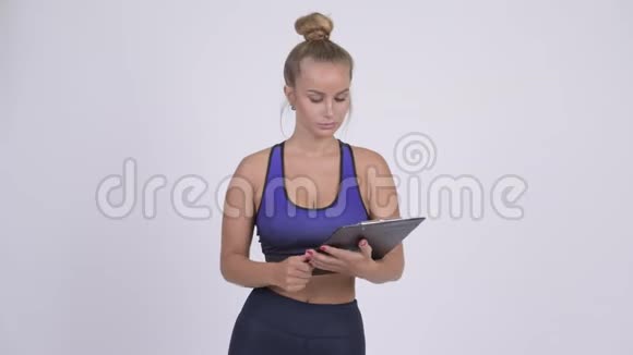 有压力的年轻女子健身教练展示剪贴板和拇指视频的预览图