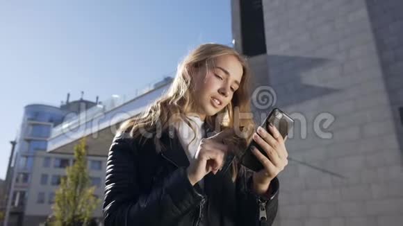 年轻漂亮的女人正在城里散步使用智能手机美丽的微笑女孩在短信上的肖像视频的预览图