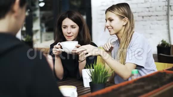 两个女孩在咖啡馆里喝咖啡男人背对着镜头坐着视频的预览图