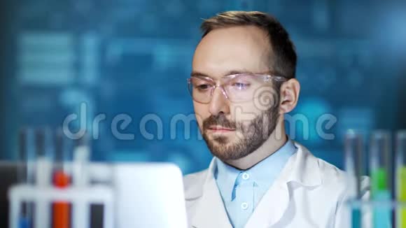 实验室里带眼镜和白大褂的微笑男科学家的中等特写镜头视频的预览图