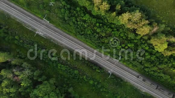 从空中俯瞰一列沿着森林中央轨道行驶的长途货运列车视频的预览图