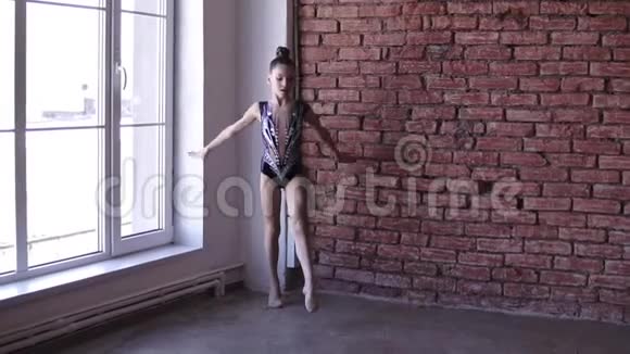 艺术少女穿着艺术紧身衣站在窗前准备跳跃从事艺术体操视频的预览图