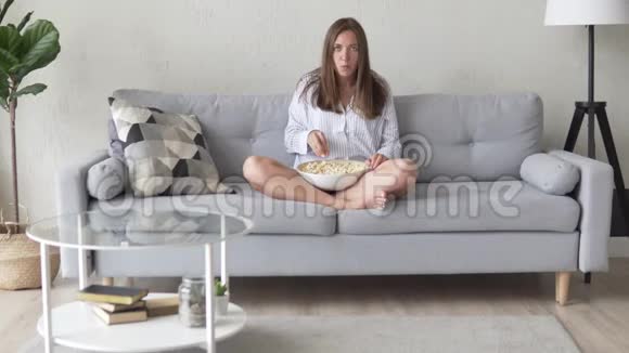 看电视吃爆米花的年轻女人视频的预览图