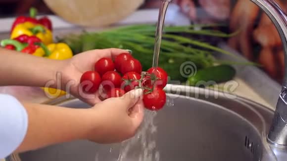 一个女人在厨房的水槽里用水冲洗樱桃番茄视频的预览图