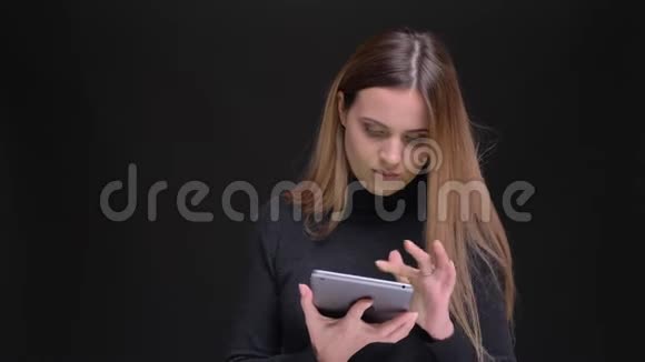 年轻的金发金发女郎专心地看着平板电脑并把它的绿色屏幕显示成黑色相机视频的预览图