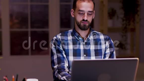 疲倦的商人在他的笔记本电脑上工作时打哈欠视频的预览图