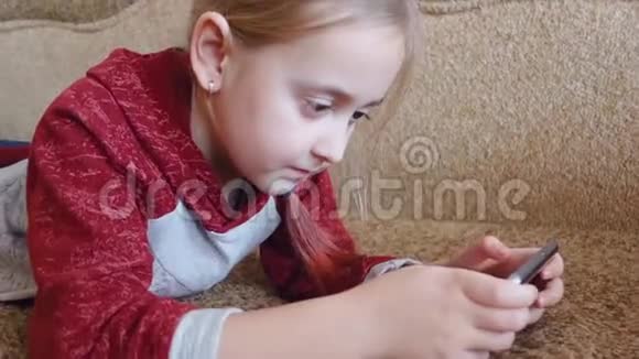 少女躺在沙发上看着手机里的视频视频的预览图