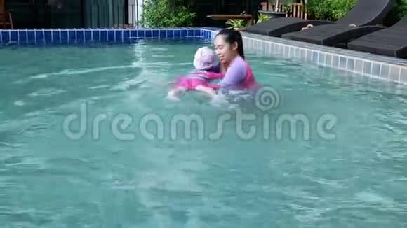 亚洲小女孩学习游泳从母亲在游泳池照顾暑假日视频的预览图