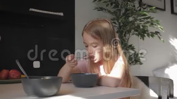 可爱的十几岁的女孩坐在餐桌前早餐吃粥健康的生活方式观念视频的预览图