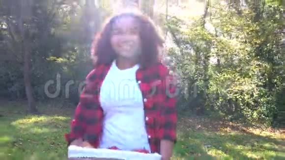 混血少女带着篮子苹果穿过灰色拖拉机穿过阳光明媚的苹果园视频的预览图