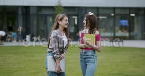 两名女大学生站在户外大城市建筑两个十几岁的女孩在校园里一起聊天视频的预览图