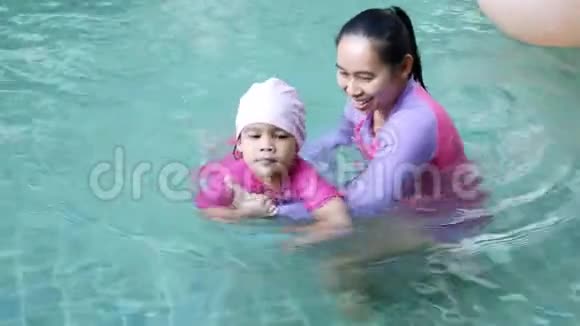 亚洲小女孩学游泳妈妈在暑假期间在游泳池里照顾孩子视频的预览图