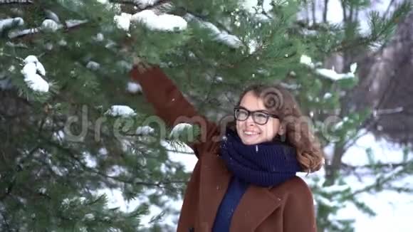 穿着针织红帽子和围巾的年轻漂亮女人在公园里享受和下雪冬季视频的预览图