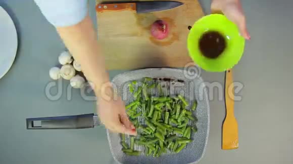 女性手将洋葱和豆子放入锅中切香姜菇视频的预览图