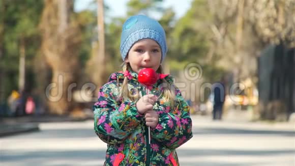 小女孩在公园里吃焦糖红苹果视频的预览图