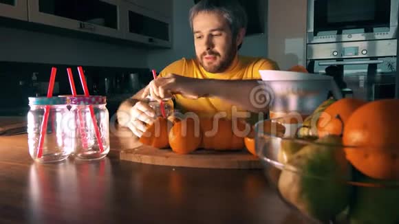 留胡子的人在家里做和喝新鲜橙汁视频的预览图