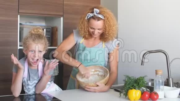 女人教孩子做面团在厨房桌子上的面粉堆里加鸡蛋视频的预览图