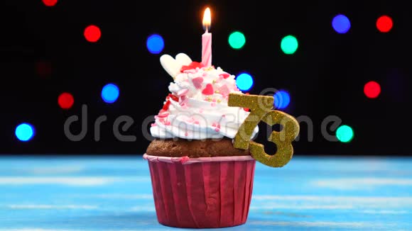 带有蜡烛的美味生日蛋糕和73号的彩色模糊灯光背景视频的预览图