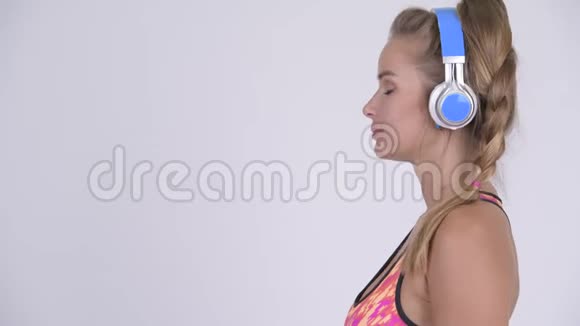 年轻美丽的金发女子听音乐的侧影视频的预览图