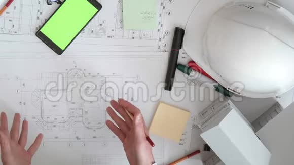 男人和女人用铅笔讨论建筑的图纸这是一个带绿色屏幕的手机一个视频的预览图