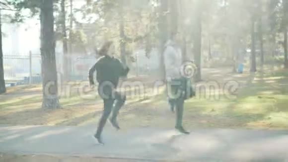 从侧面看漂亮的年轻人女孩和男人在公园里做运动在温暖的道路上一起跑步和跳跃视频的预览图
