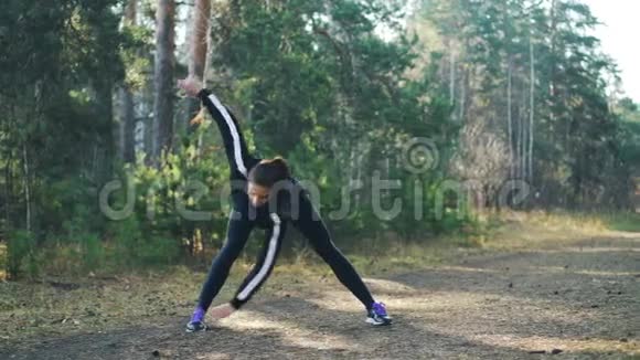 迷人的年轻女运动员正穿着现代黑色运动服在阳光明媚的秋天在公园里做运动苗条的女孩视频的预览图