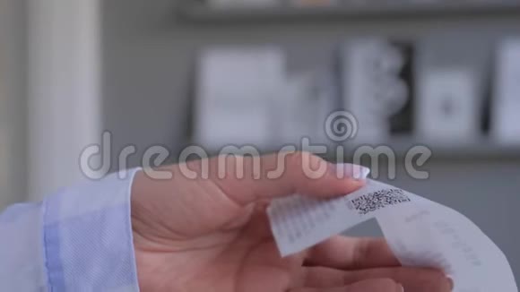 女士使用智能手机扫描现金商店收据纸上的QR码视频的预览图