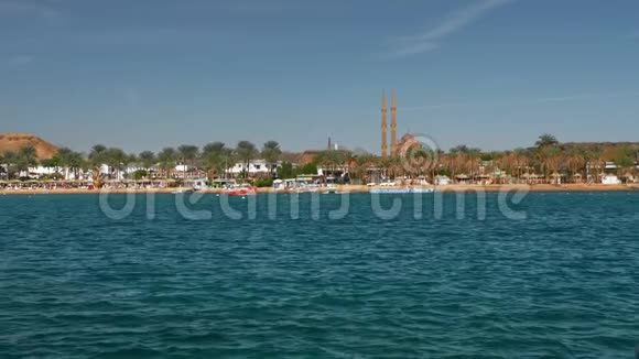 在阳光明媚的一天在蓝色美丽的大海上移动快艇在棕榈树和度假村的背景下视频的预览图