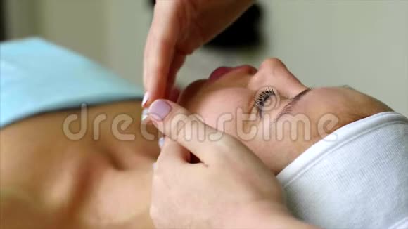 按摩治疗师美容师为美容院的妇女做脸颊按摩视频的预览图