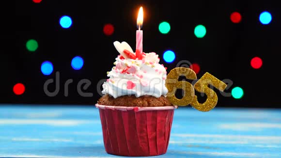 带有蜡烛的美味生日蛋糕和65号的彩色模糊灯光背景视频的预览图