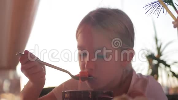 孩子们在咖啡馆喝汤小女孩吃晚饭美丽的微笑女孩从盘子里吃汤视频的预览图