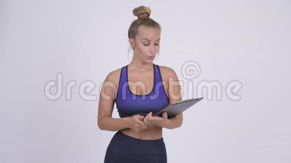 快乐的年轻女子健身教练展示剪贴板竖起大拇指视频的预览图