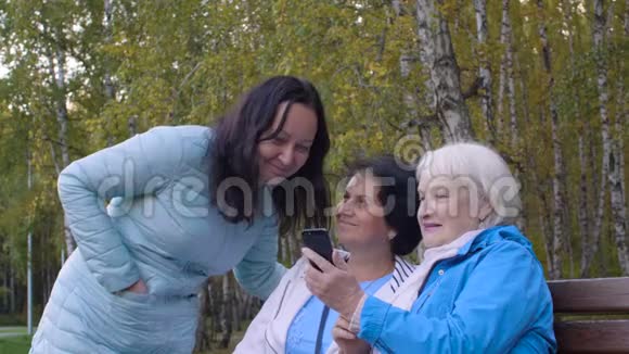 女人用手机在秋天公园里欢笑视频的预览图