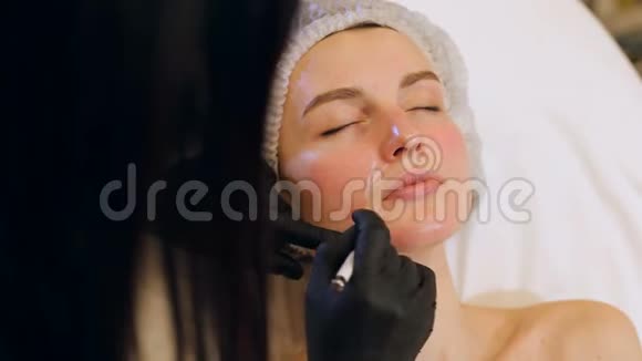 美容师在病人脸上画一支白色铅笔的轮廓视频的预览图