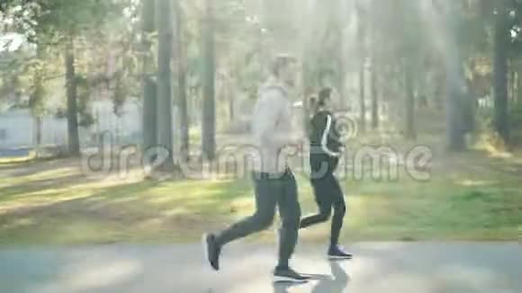 穿着运动服的女孩和男孩在秋天的公园里慢跑享受健康的活动和美丽的自然树木和视频的预览图