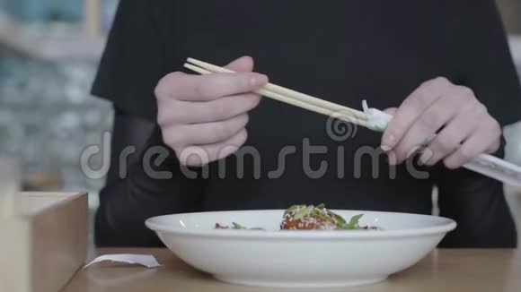 不认识的年轻女人从包裹里拿出筷子分成两块准备吃歪着的视线视频的预览图