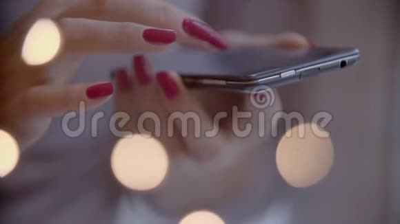 带红色美甲的迷人女人在智能手机上工作并在笔记本上做笔记圣诞前夜视频的预览图