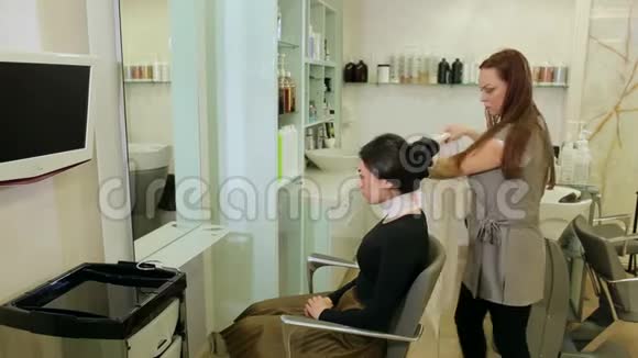 女理发师在剪发前在女孩脖子上戴上美发项圈视频的预览图