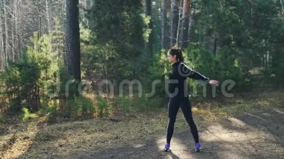 穿着现代运动服的漂亮年轻女子正在公园里独自锻炼热身手臂和身体肌肉视频的预览图