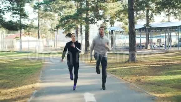 漂亮的一对漂亮的女孩和留胡子的家伙正在公园里一起跑步和跳跃积极的生活方式视频的预览图